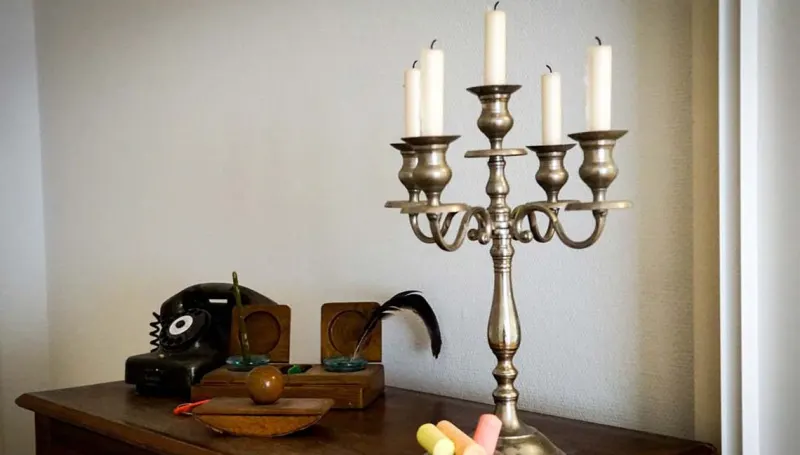 Silberner Kerzenleuchter und altes Telefon auf einer Holzkommode